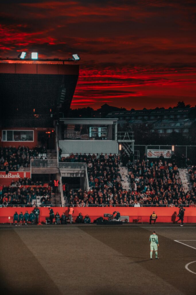 pexels-photo-1657322-1657322 A vibrant soccer match in a stadium with spectators and a stunning sunset backdrop.
